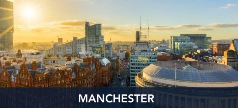 A panoramic view of Manchester's cityscape during sunset, showcasing a mix of modern and historic buildings under a clear sky with the word "Manchester" overlaid at the bottom.